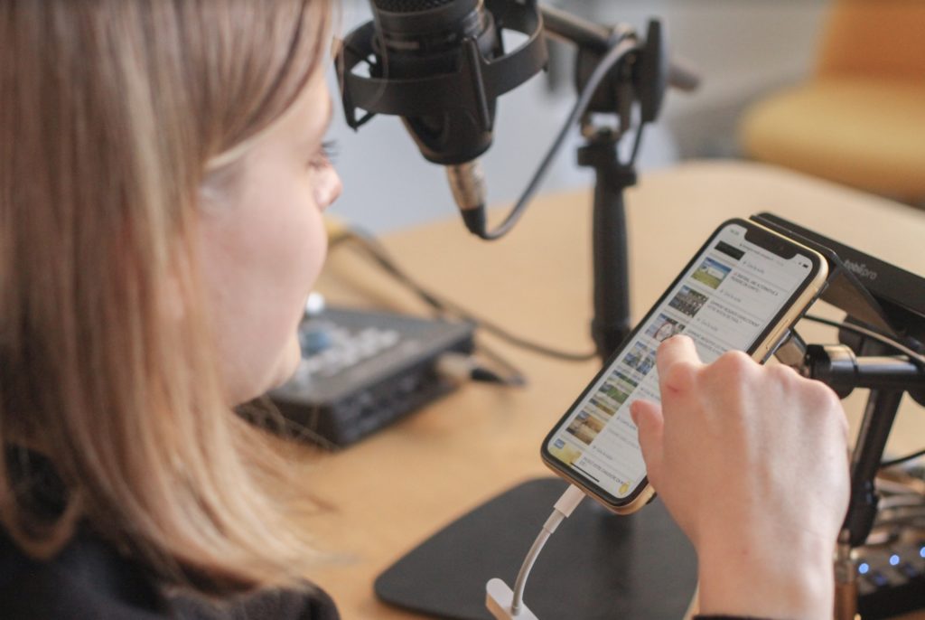 Une personne testant une application mobile tout en parlant dans un microphone, illustrant un processus d'audit UX avec des outils de test utilisateur.